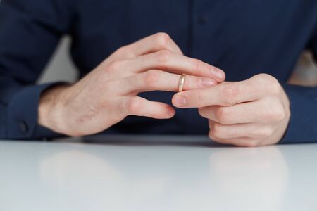 Young man is taking off the wedding ring. Close up view. Divorce concept.の写真素材
