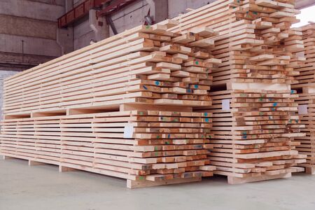 Warehouse or factory for sawing boards on sawmill indoors. Wood timber stack of wooden blanks construction material. Logging Industry.の写真素材