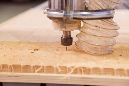 Milling a wooden board. Processing of wood panels on CNC coordinate milling woodworking machines. CNC woodworking machineの写真素材