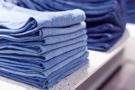 Stacks of blue jeans pants on a shelf in shopの写真素材