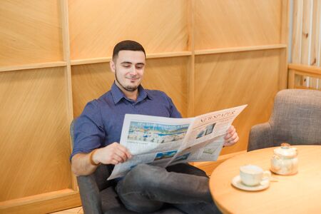 Handsome young man enjoying in cafe reading newspapers and drinking coffee.の写真素材