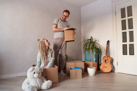 Young family make inventory of things during the move. a man with a folder records the nomenclature...