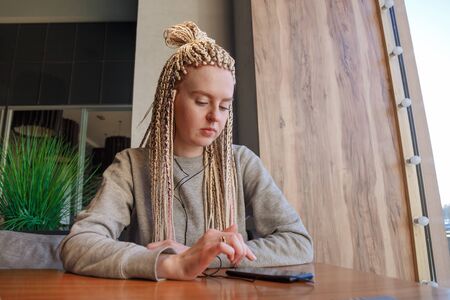 Worried young hipster woman in cafe. Lateness or punctuality concept.の写真素材