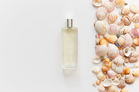 Glass perfume bottle and seashells isolated on white with copyspace, top view, flat lay