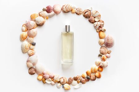 Perfume bottle in frame made of seashells isolated on white, top view, flat layの写真素材