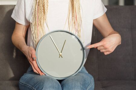 Woman point to clock in her hand. Almost one ourの写真素材