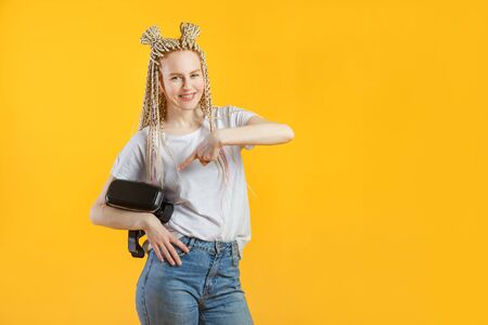 Smiling happy young woman with VR-headset glasses in hands on yellow backgroundの写真素材