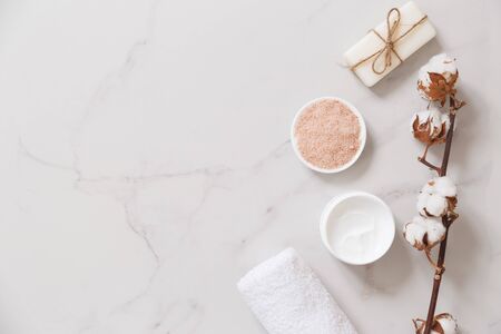 Spa cosmetics set on white marble background from above. Color sea salt, cream, soap and cotton towel. Beauty blogger concept. Copy spaceの写真素材