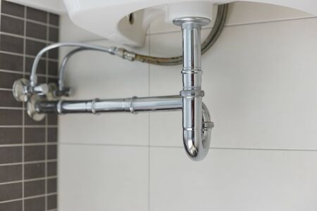 metal sink siphon and drain in white bathroomの写真素材