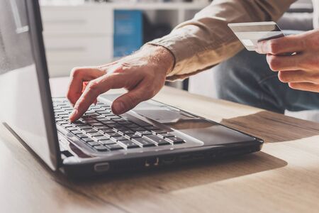 Man enters his bank card details to pay online or other financial transactions, close-up view on handsの写真素材