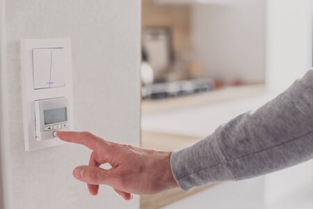 Men hand setting the temperature on control panel of DHW or central heating.の写真素材