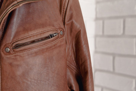 Brown leather jacket hanged on white wall hanger