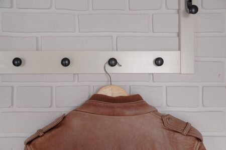 Brown leather jacket hanged on white wall hanger.の写真素材