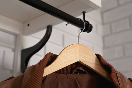 Brown leather jacket hanged on white wall hanger.の写真素材