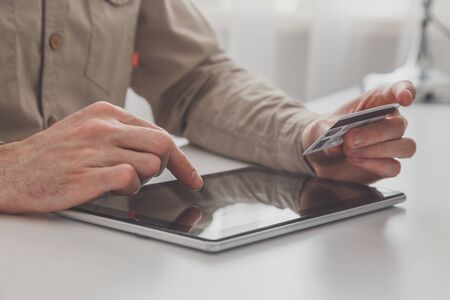 Man holding tablet pc and credit card at the table, shopping online.の写真素材