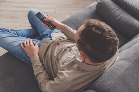 Man lying on sofa watching TV at home.の写真素材