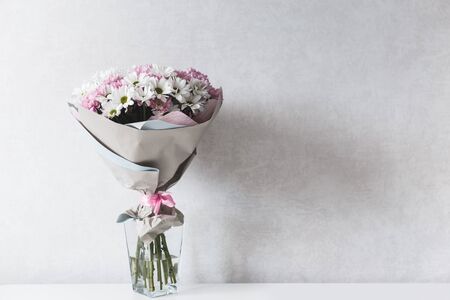 Bouquet of white and pink chrysanthemums in glass vase on tableの写真素材