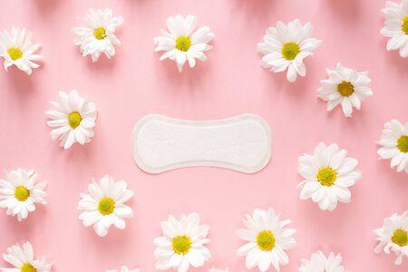 Panty liner with chamomile flowers on a pink background. Menstruation and women everyday hygiene concept. Flat lay, top viewの写真素材