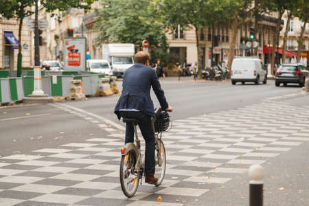 Businessman riding bicycle to work on Parisian street.のeditorial素材