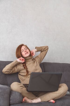 Young woman is stretching after finished the work or online conference on sofa. Freelance, Working at homeの写真素材