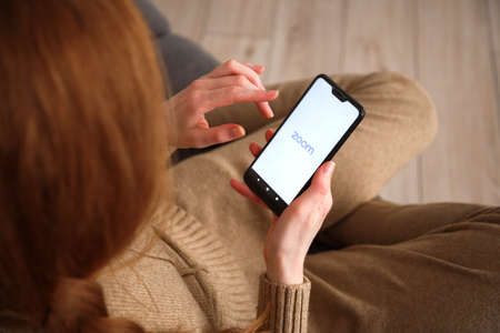 Minsk-Belarus: May 27, 2020: close up view on smartphone with zoom logo in womans hands. Social media concept.のeditorial素材