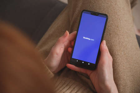 Minsk-Belarus: May 27, 2020: close up view on smartphone with Booking logo in womans hands. Social media conceptのeditorial素材