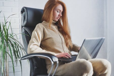 Young caucasian woman using laptop working from home, freelancer, social distancing and remote workの写真素材