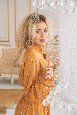 Luxury african mixed girl in fashionable dress posing near crystal chandelier in interior.の写真素材