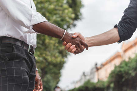 Handshake between african and a caucasian man outdoors.の写真素材