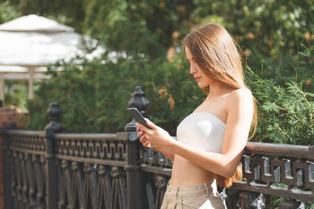 Young stylish pretty woman with smartphone in the city streets.の写真素材