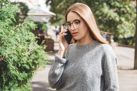 Fashion girl in eyeglasses on the street calling on mobile phone.の写真素材