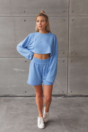 Young caucasian blonde in a fashionable sportswear look on woman. Blue shorts and sweatshirt.の写真素材