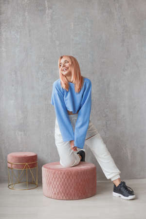 Portrait of sexy fit woman wearing ripped pants sportswear standing at concrete wallの写真素材