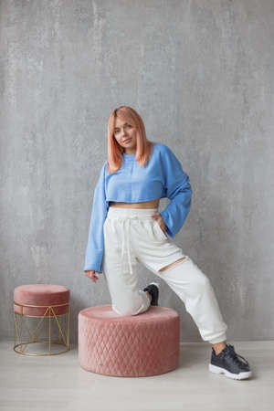Portrait of sexy fit woman wearing ripped pants sportswear standing at concrete wallの写真素材