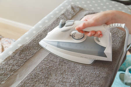 Hands with modern iron with steam system ironing clean, crumpled towel.の写真素材