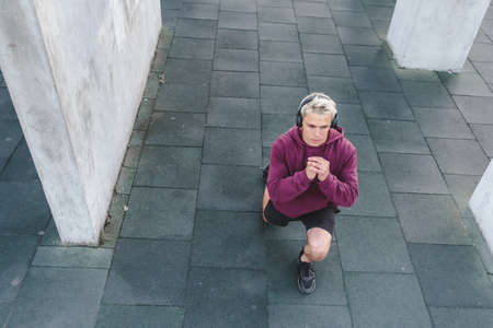 Young athletic man  listen to music and warming up outdoors.の写真素材