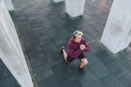 Young athletic man with headphones and warming up outdoors.の写真素材