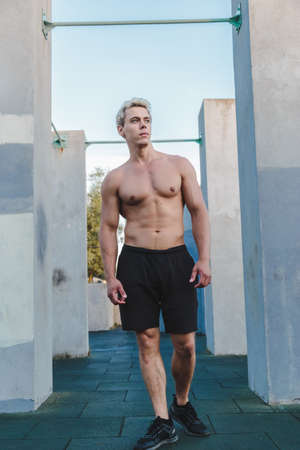 Natural portrait of young athletic man standing near concrete wall.の写真素材