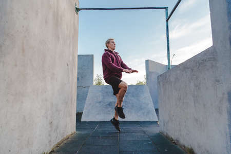 Young sportsman running on the spot outdoor for warming up before parkour trainingの写真素材