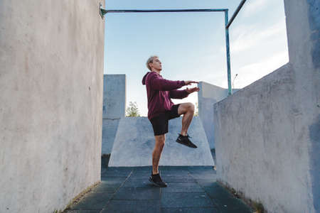 Young sportsman running on the spot outdoor for warming up before parkour trainingの写真素材