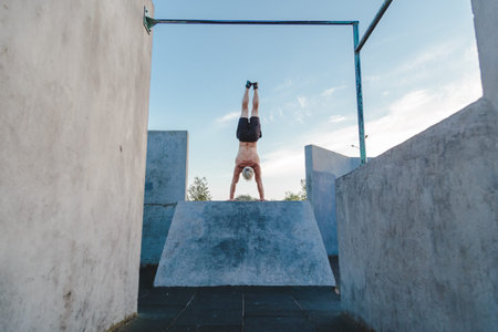 Handstand yoga pose by athlete man on the sport ground outdoors, natural lifestyle photo.