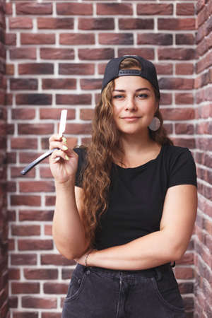 Young caucasian professional barber woman holding a straight razorの写真素材