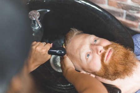 Barber woman washes customer man head. Concept barbershop.の写真素材