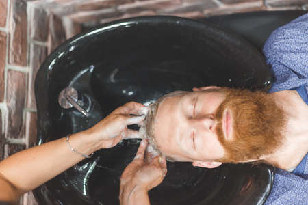 Barber woman washes customer man head. Concept barbershop.の写真素材