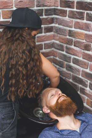 Barber woman washes customer man head. Concept barbershop.の写真素材