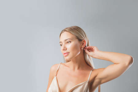 Beautiful blonde woman face close up portrait young studio on grayの写真素材