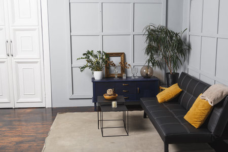 Bright apartment interior with black leather sofa, decorated wall lamp and table.の写真素材
