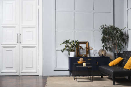 Bright apartment interior with black leather sofa, decorated wall lamp and table.の写真素材