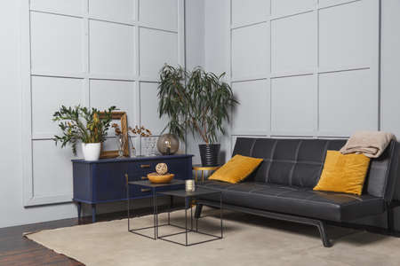 Bright apartment interior with black leather sofa, decorated wall lamp and table.の写真素材