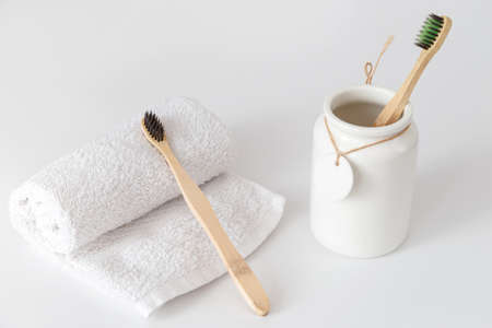 Ceramic cup with wooden toothbrush and on white towel with copy space. Ecological material and dental careの写真素材